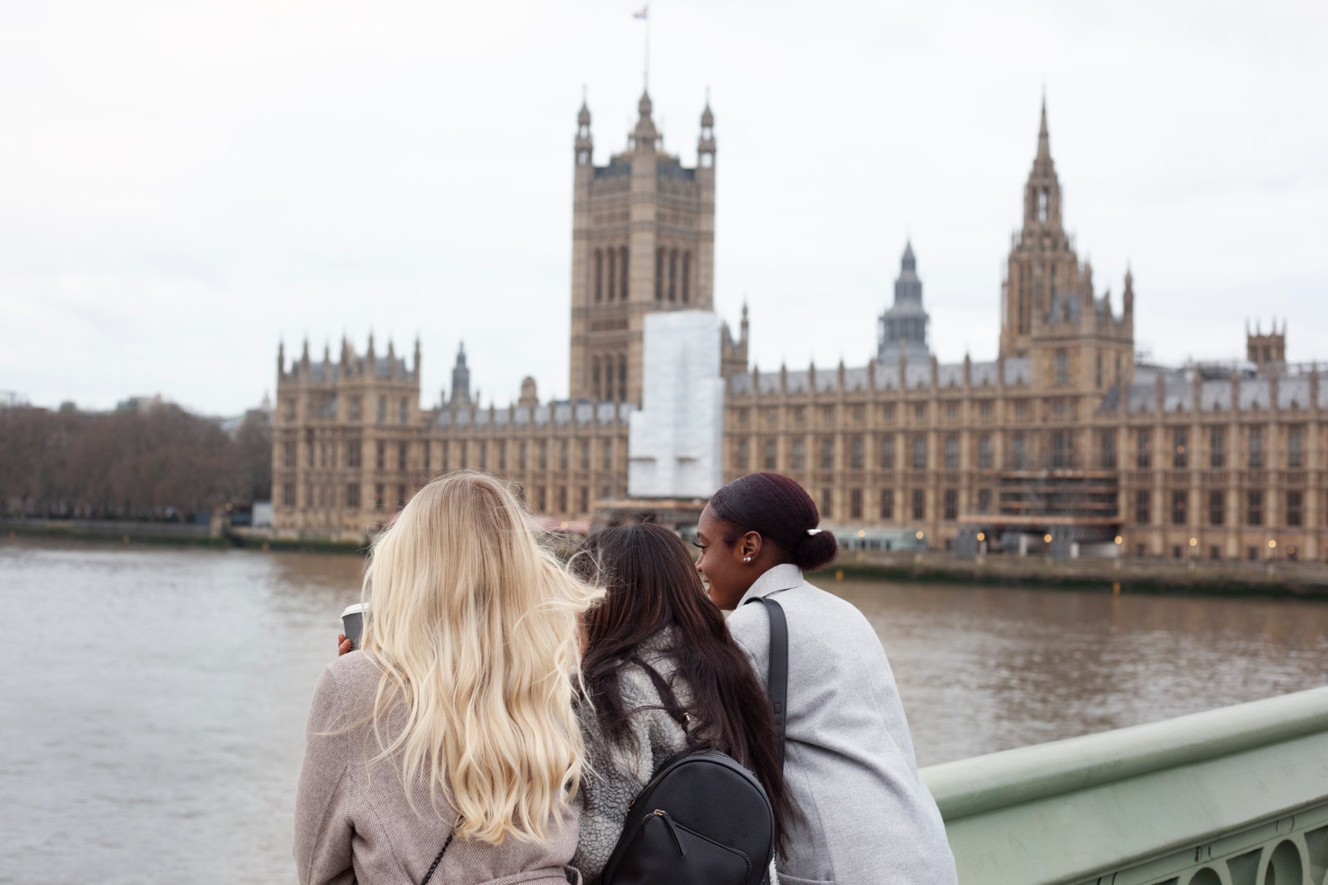 Tre ragazze sulla riva del Tamigi a Londra, con il Palazzo di Westminster alle spalle